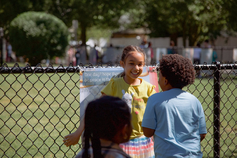 Students stand in front of a fence.