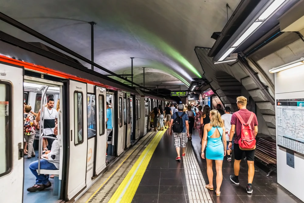 People walking to board a train in Barcelona subway station.