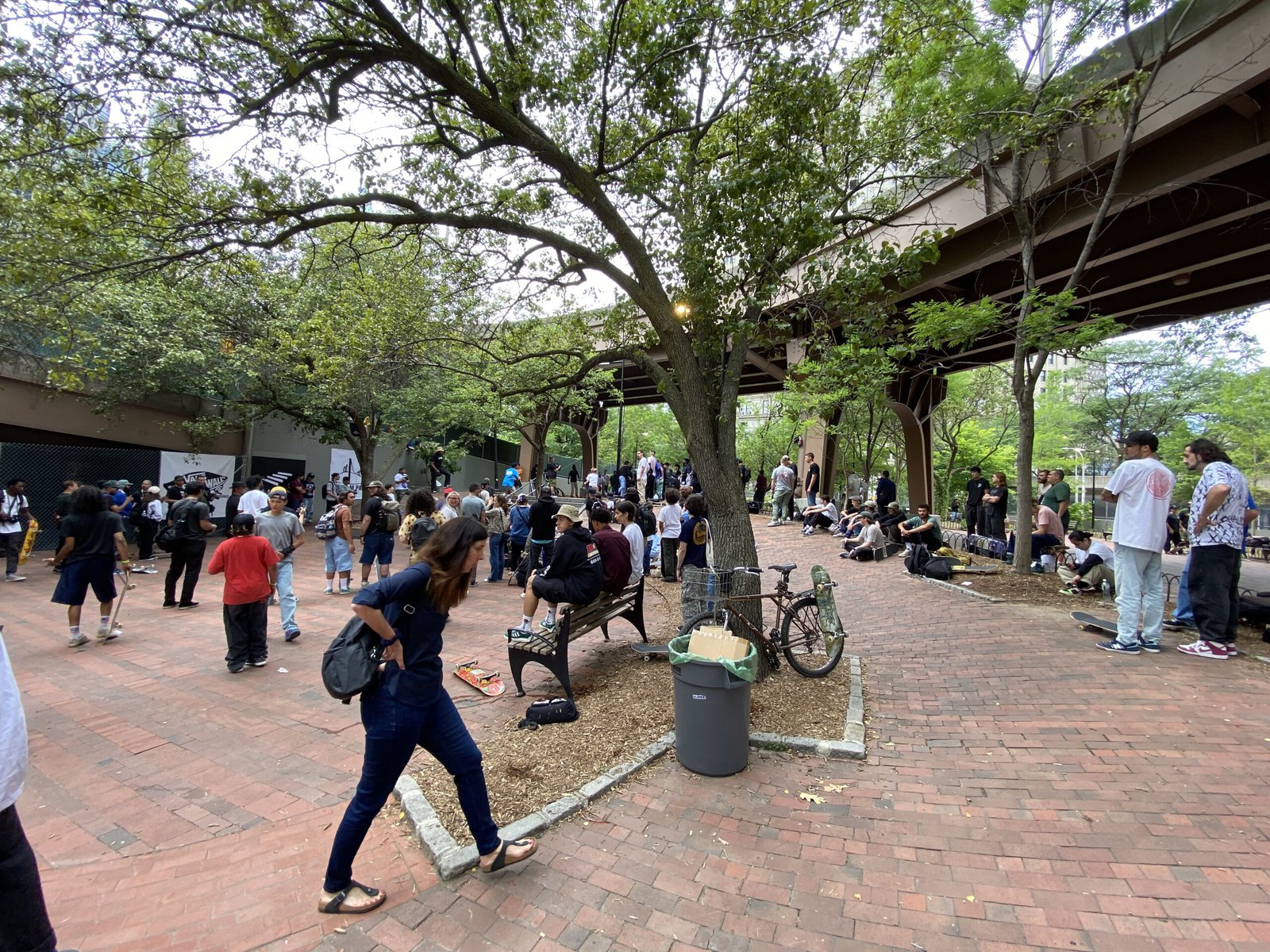 People walk in a park under the Brooklyn Bridge.