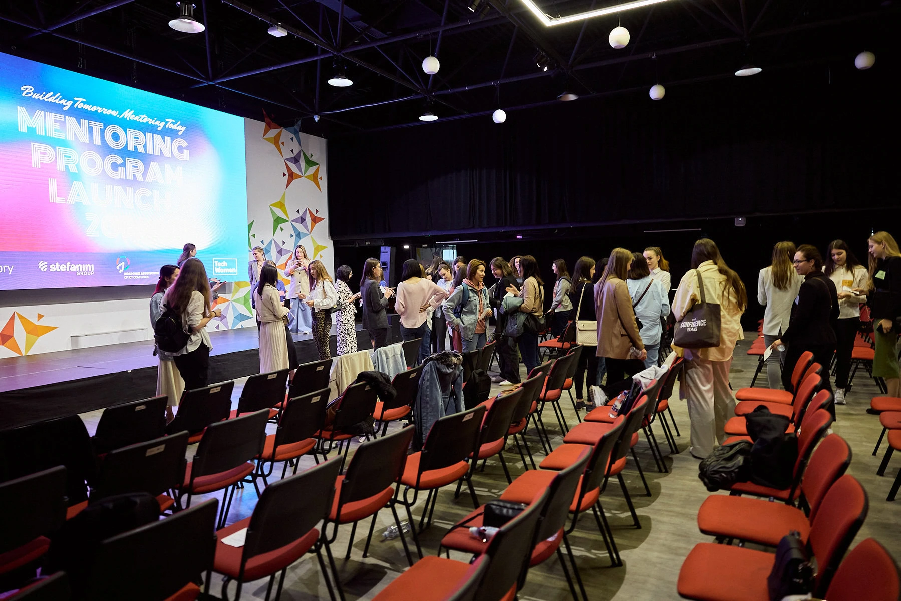 A group of women talking after a presentation about tech careers.