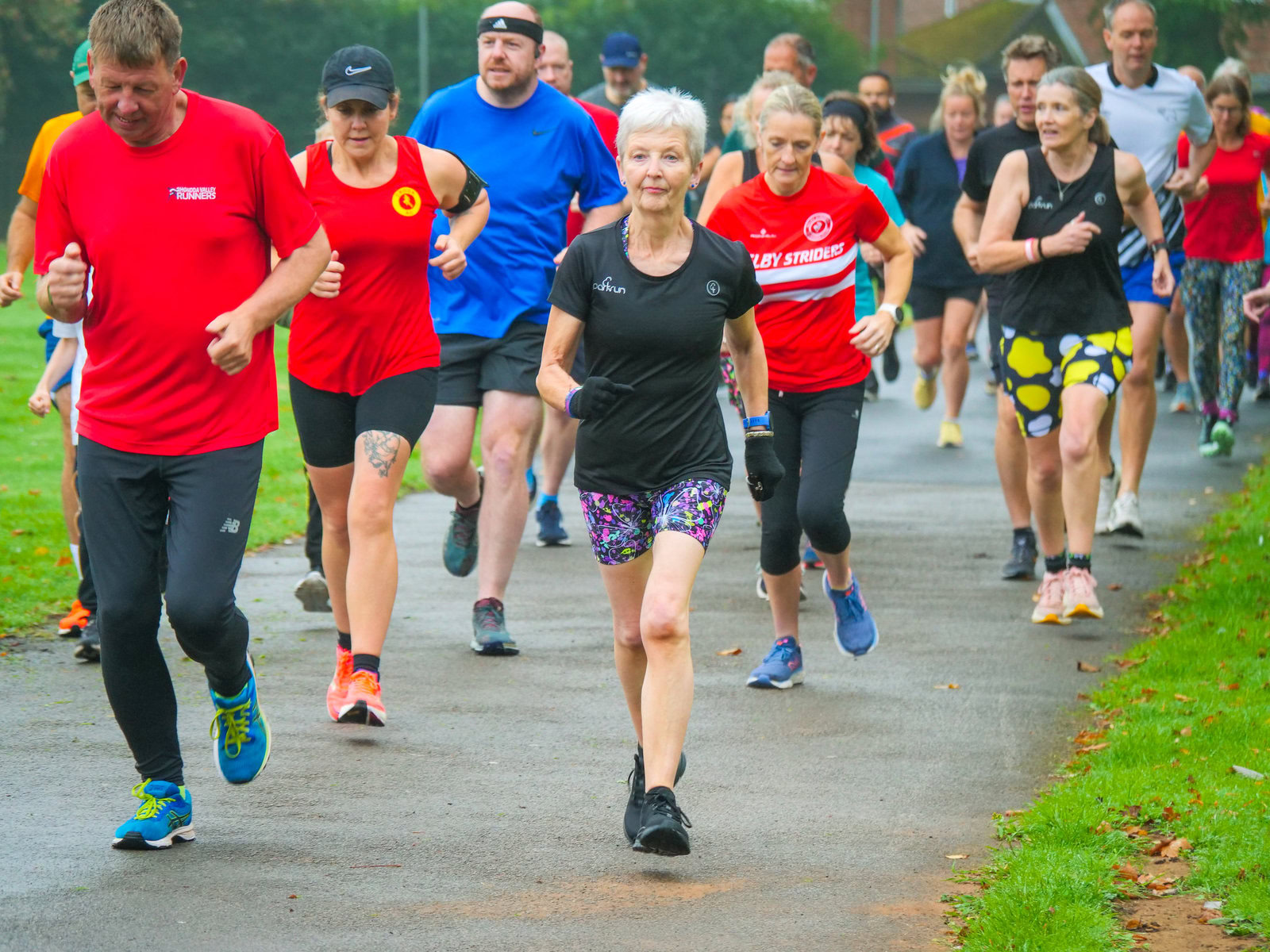 A crowd of runners in a park on a wet-looking day.