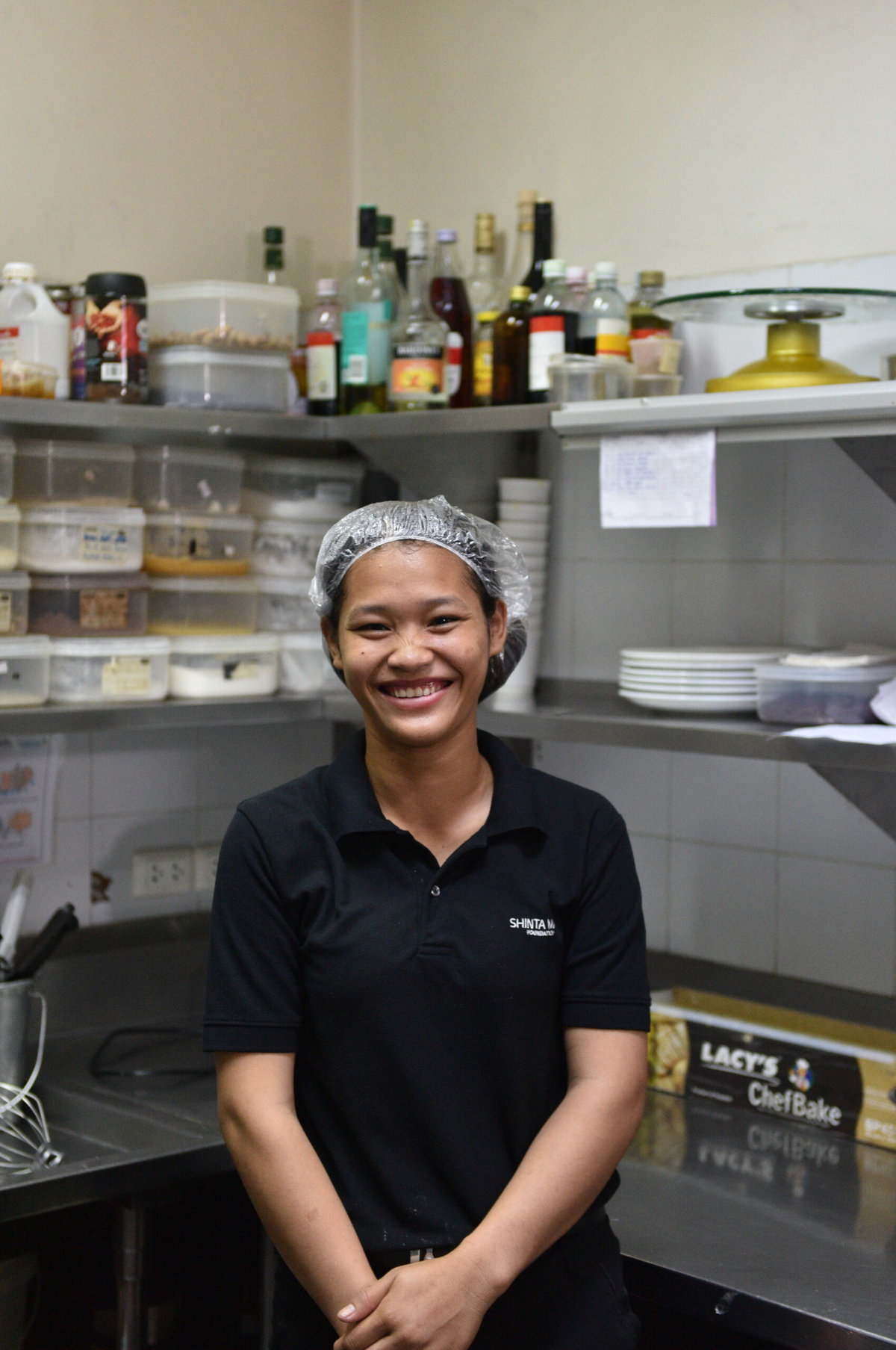 A hospitality student working in the culinary area poses wearing a plastic hair cover.