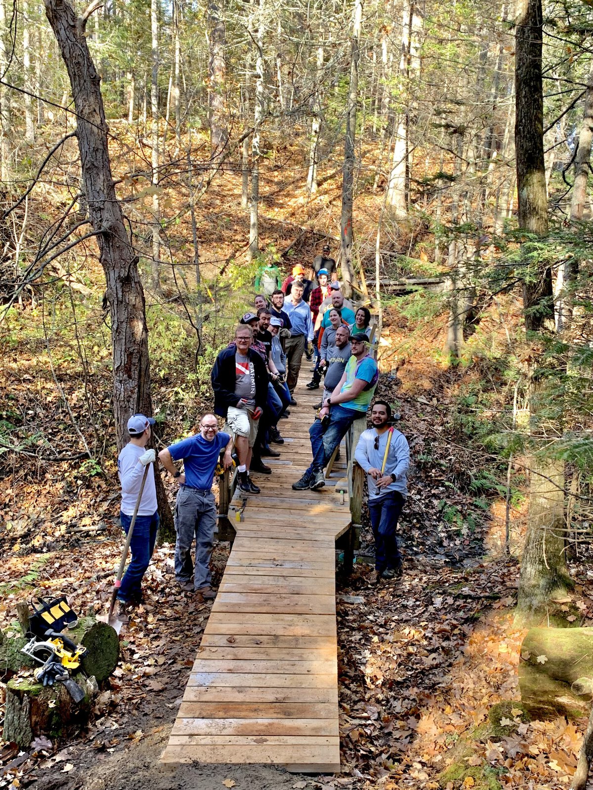 Volunteers pose while working on a wooden trail.