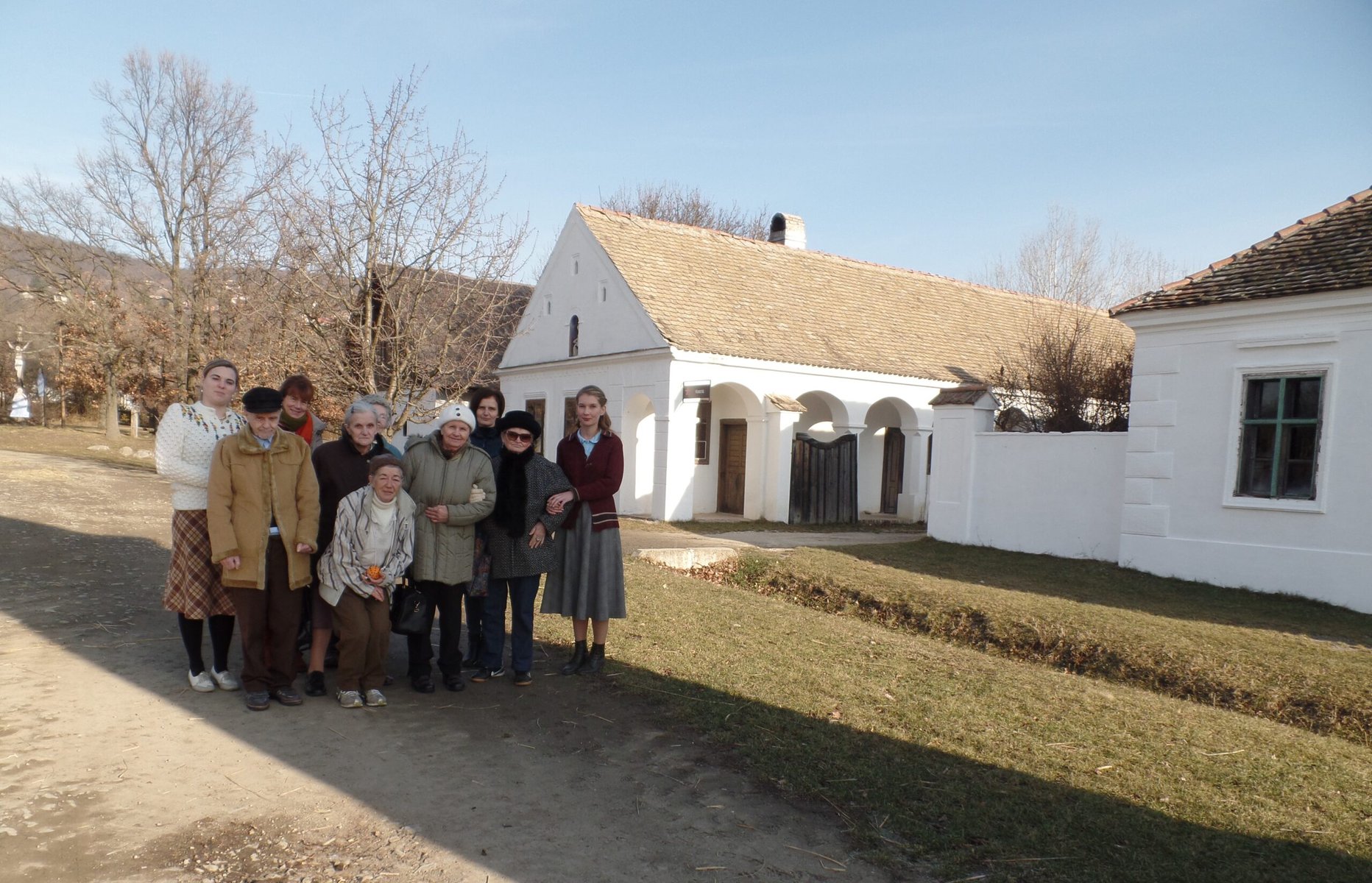 A group of older people stand together outside of a museum.