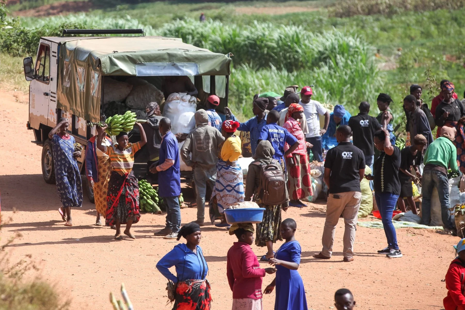 Ox truck in a Rwandan market with people unloading produce.