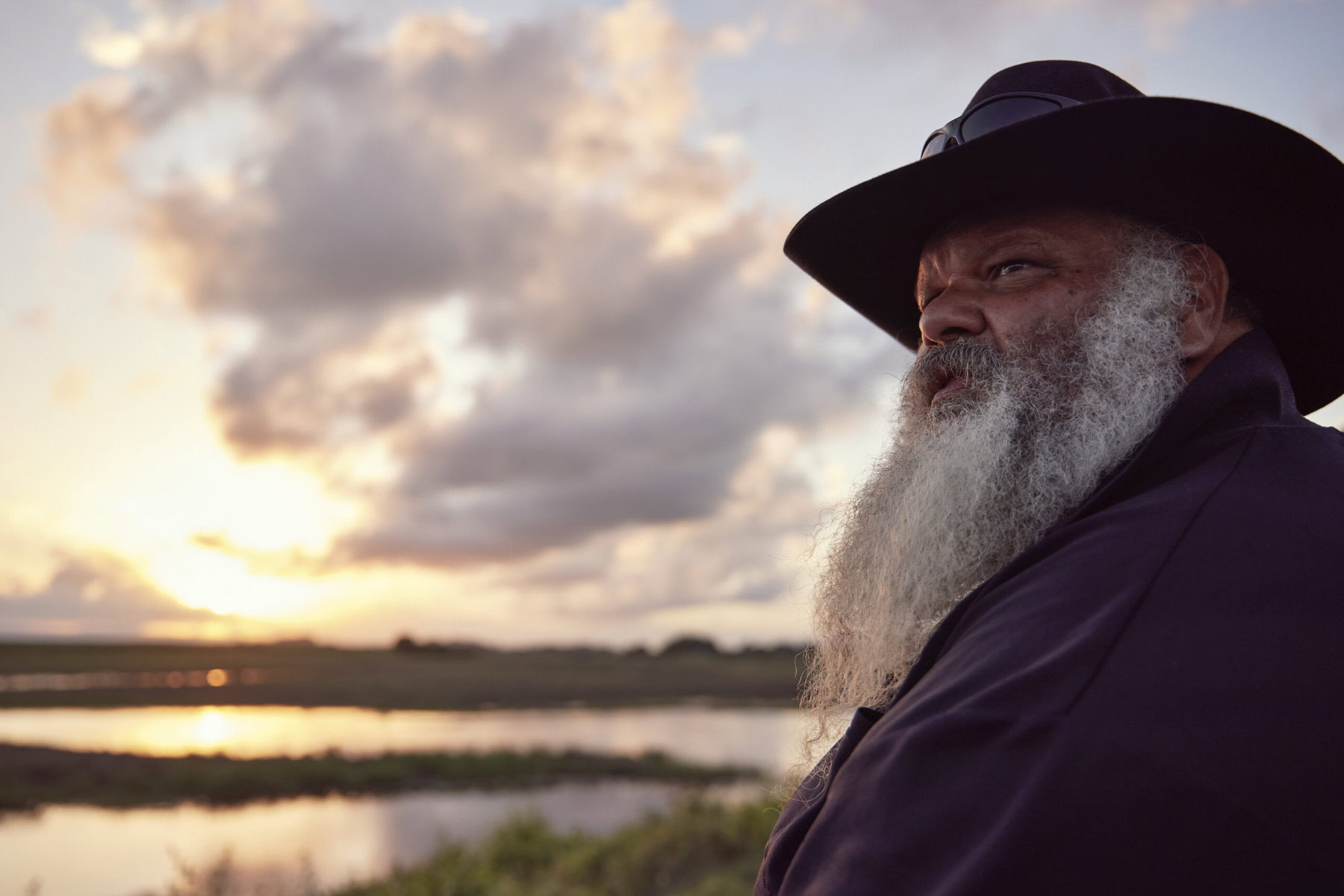 Jacob Cassady stands speaking in front of the wetlands at sunset.