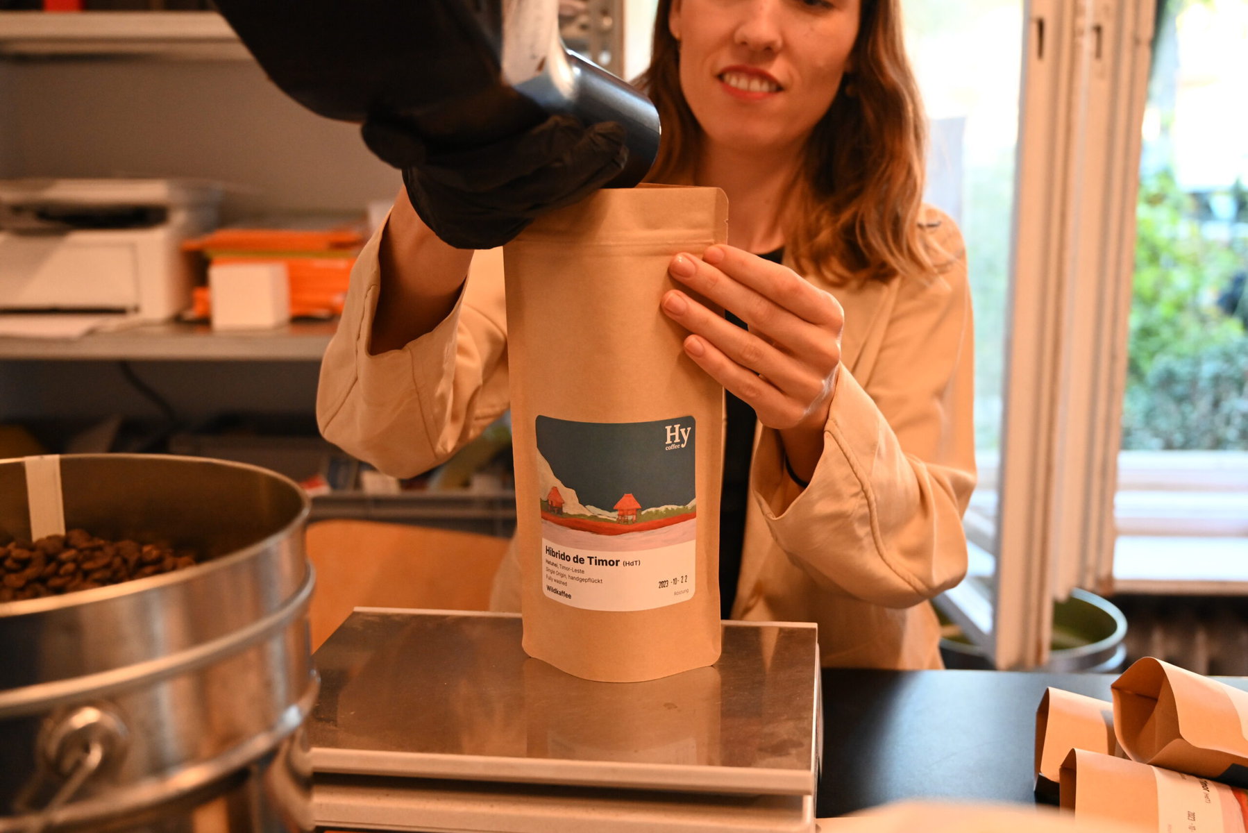 A woman pours coffee beans into a HyCoffee bag.