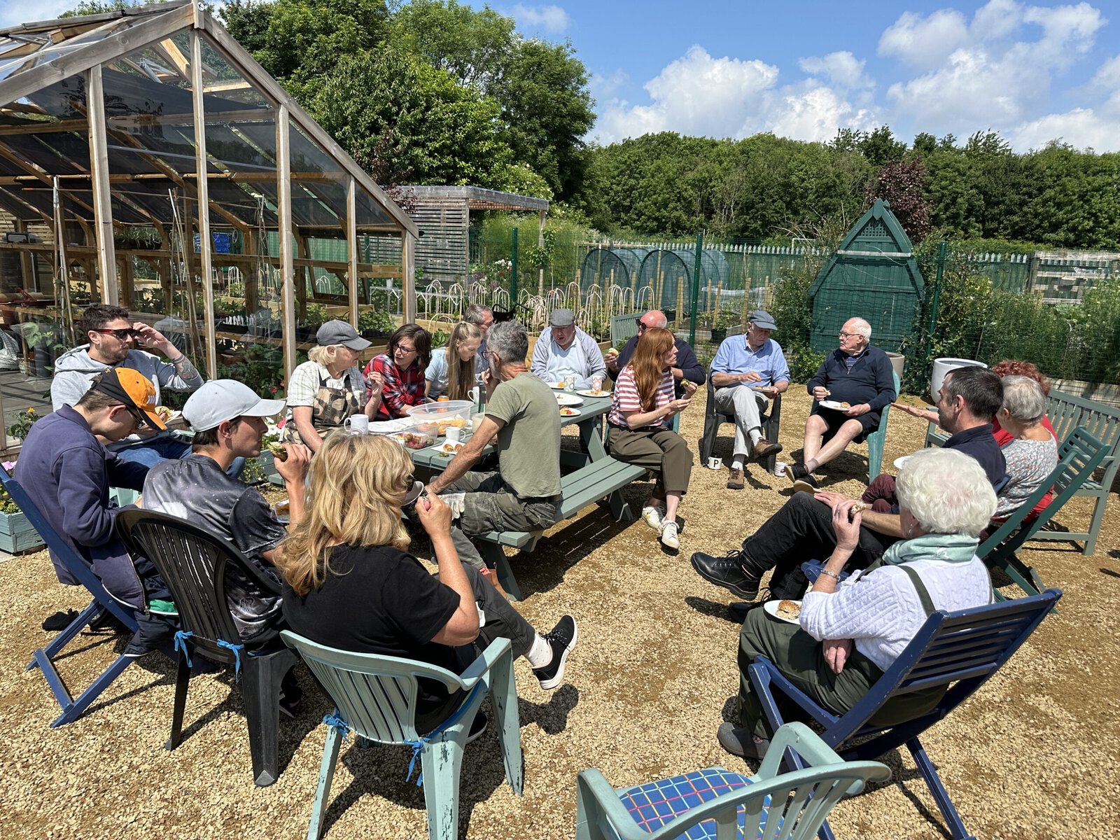 People sit and have tea outside a garden.