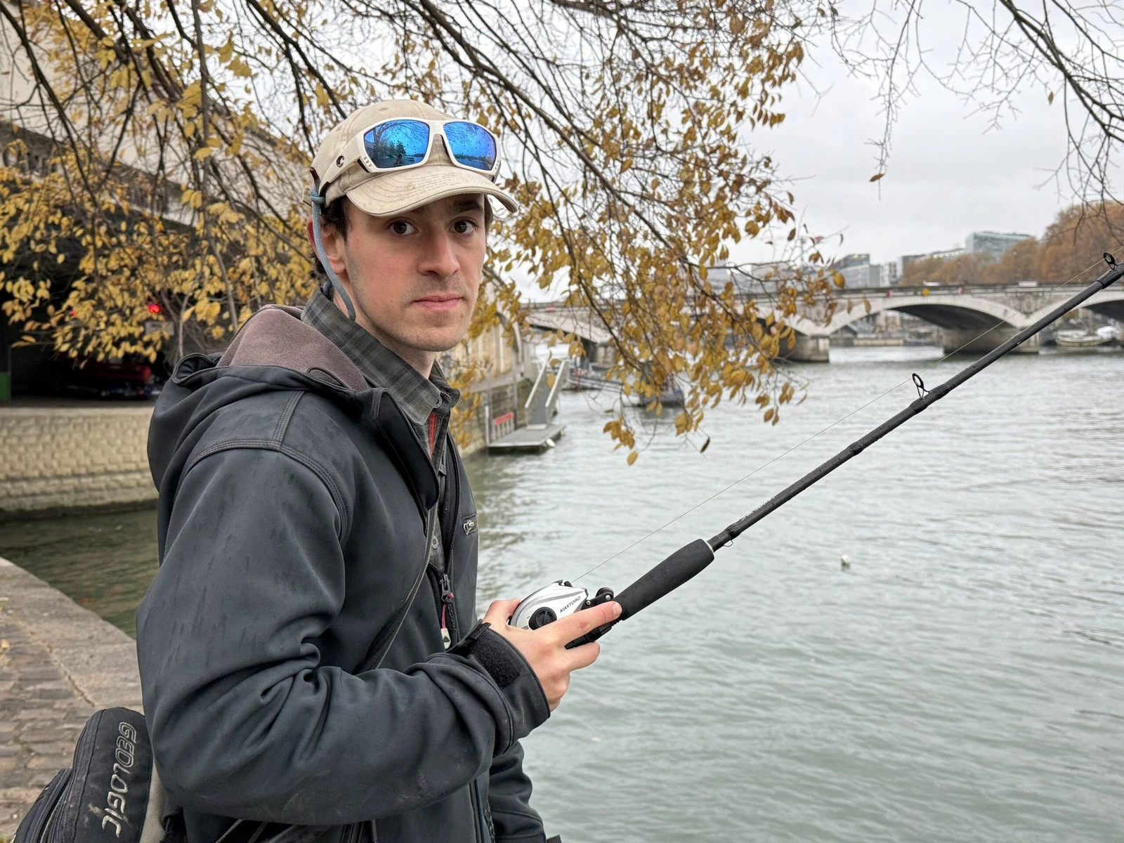 A fisherman stands with his fishing pole by the Seine.