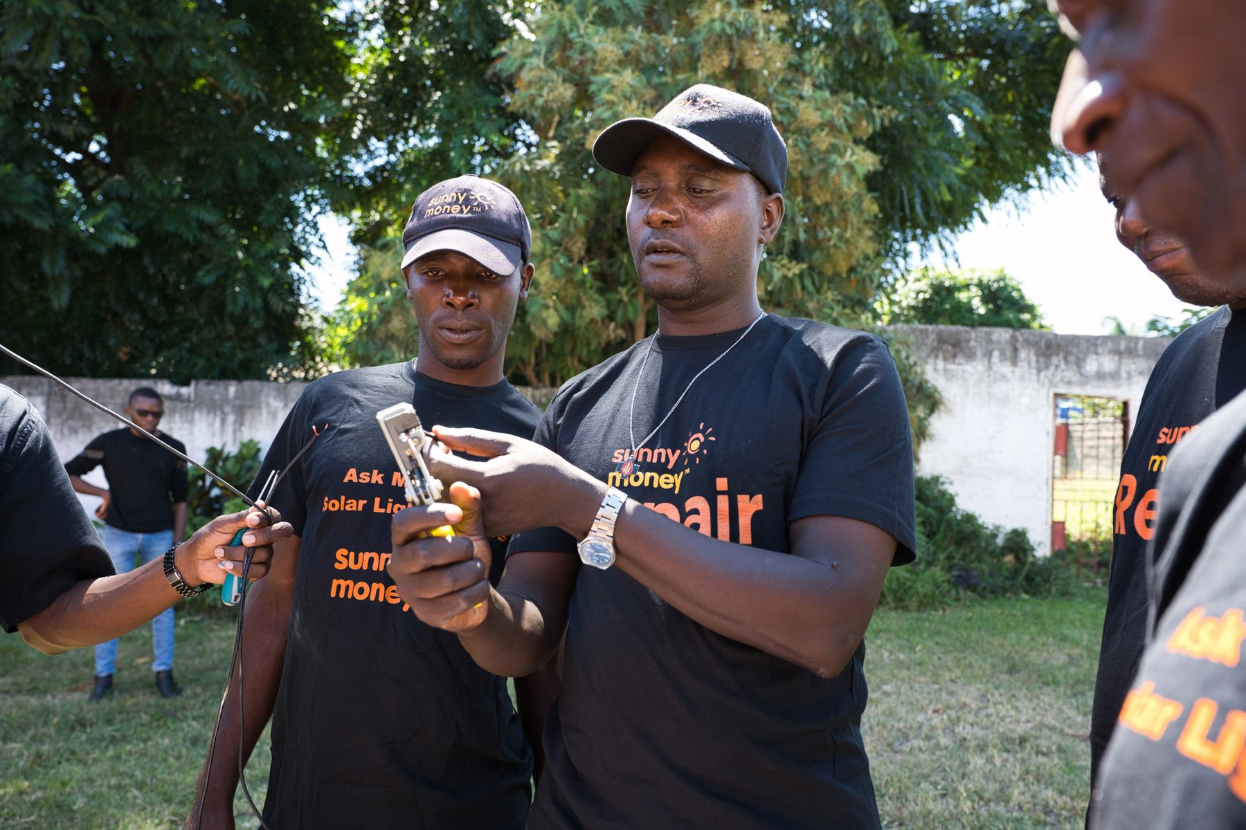 Two men look at a device to repair it.