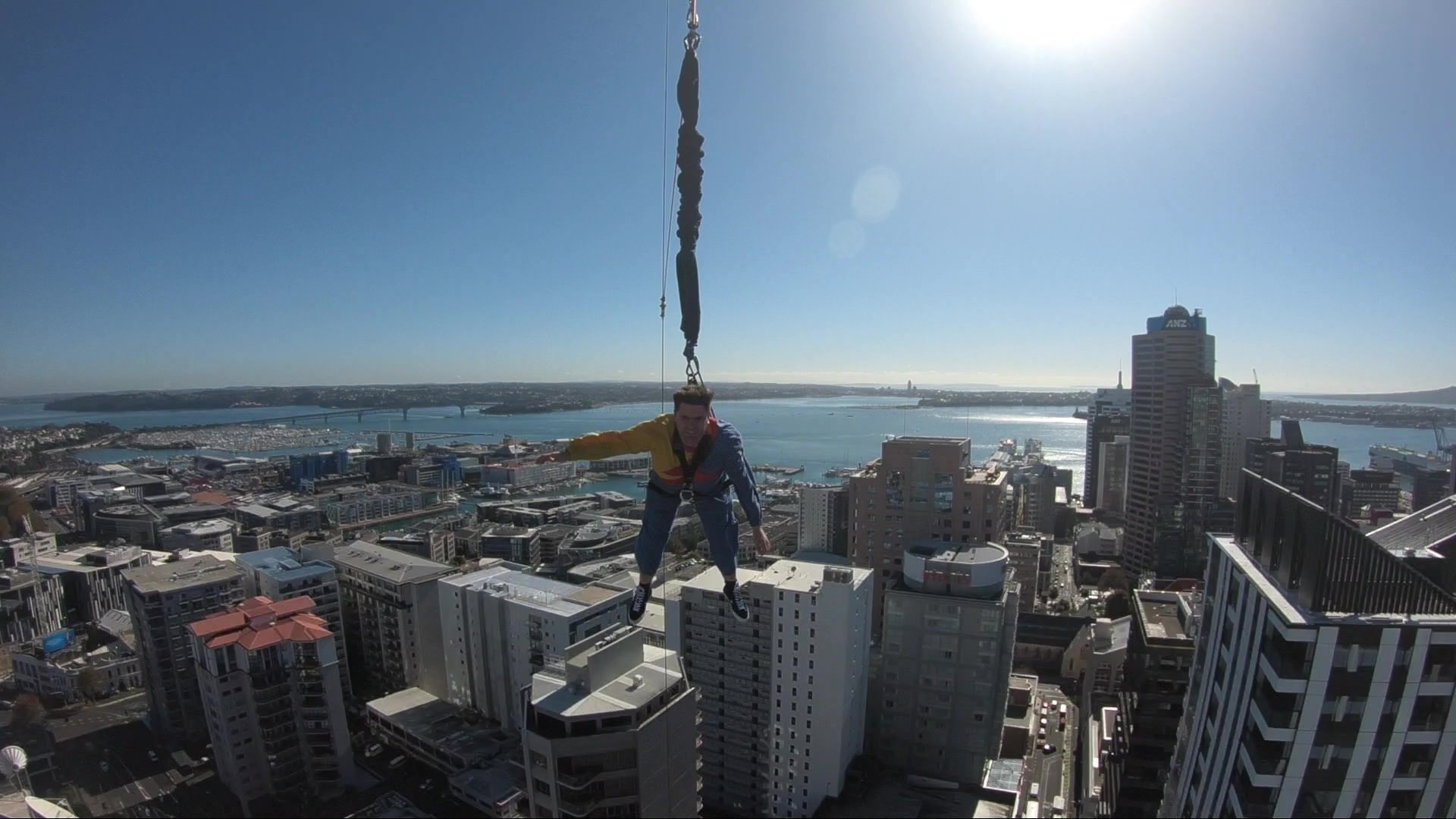 Mark Colman skydiving in Auckland with a view of buildings and water below him.