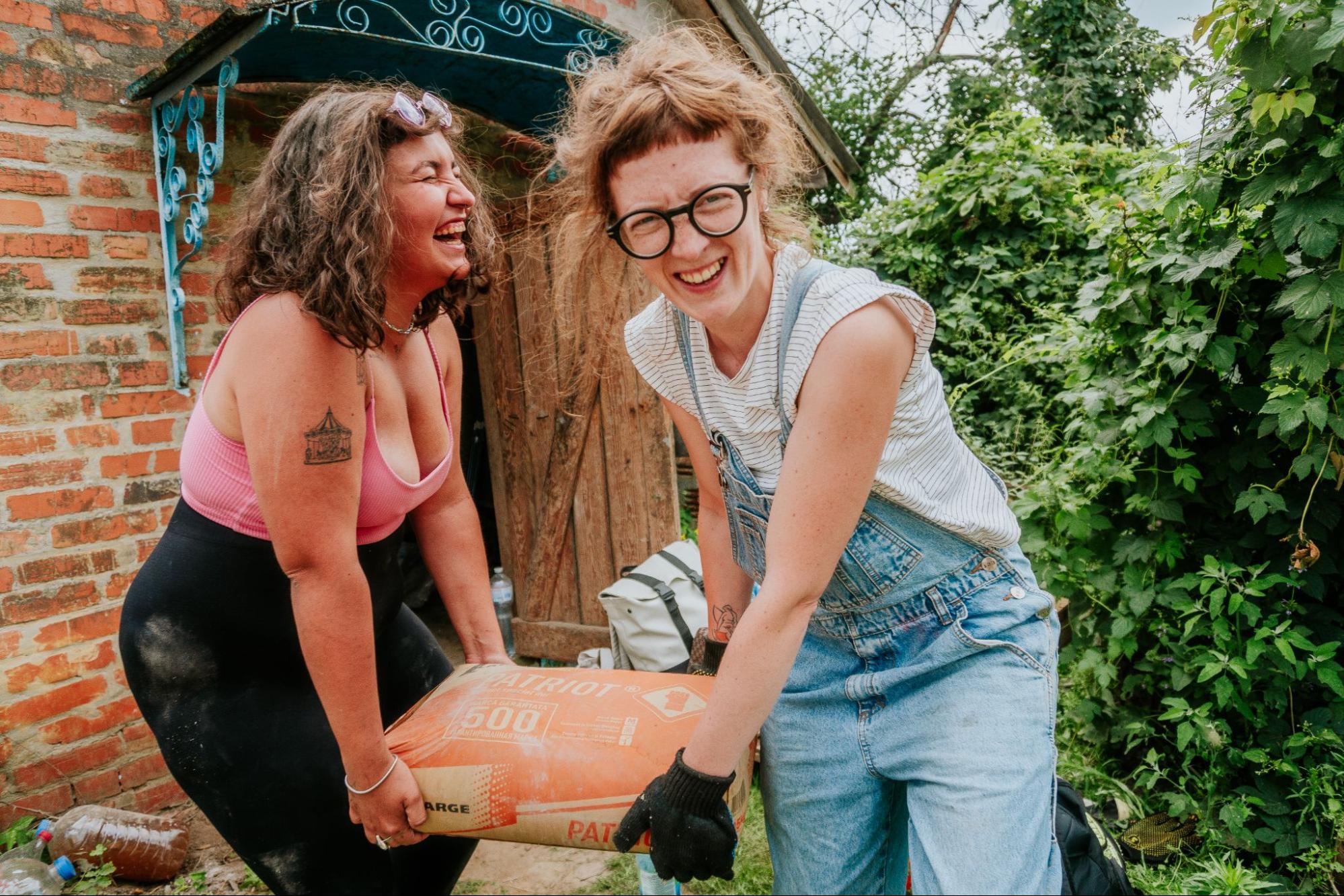 Two Repair together volunteers laughing while they carry materials.