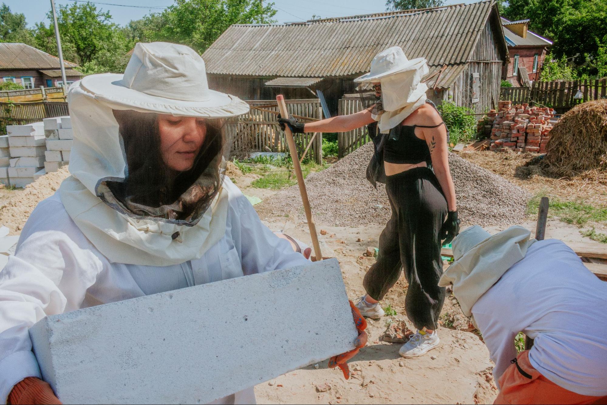 Women wearing protective hats and carrying building materials.