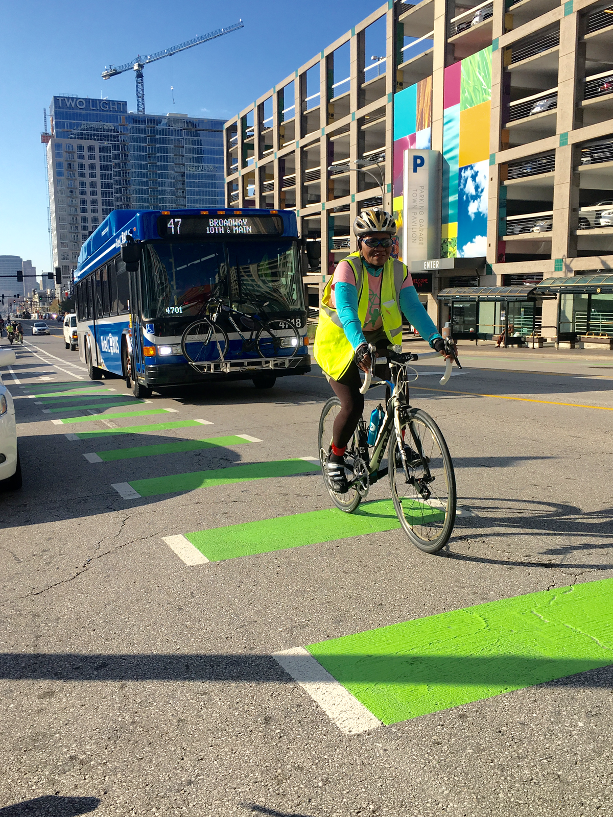 A person rides a bike in a green bike lane ahead of a public bus.