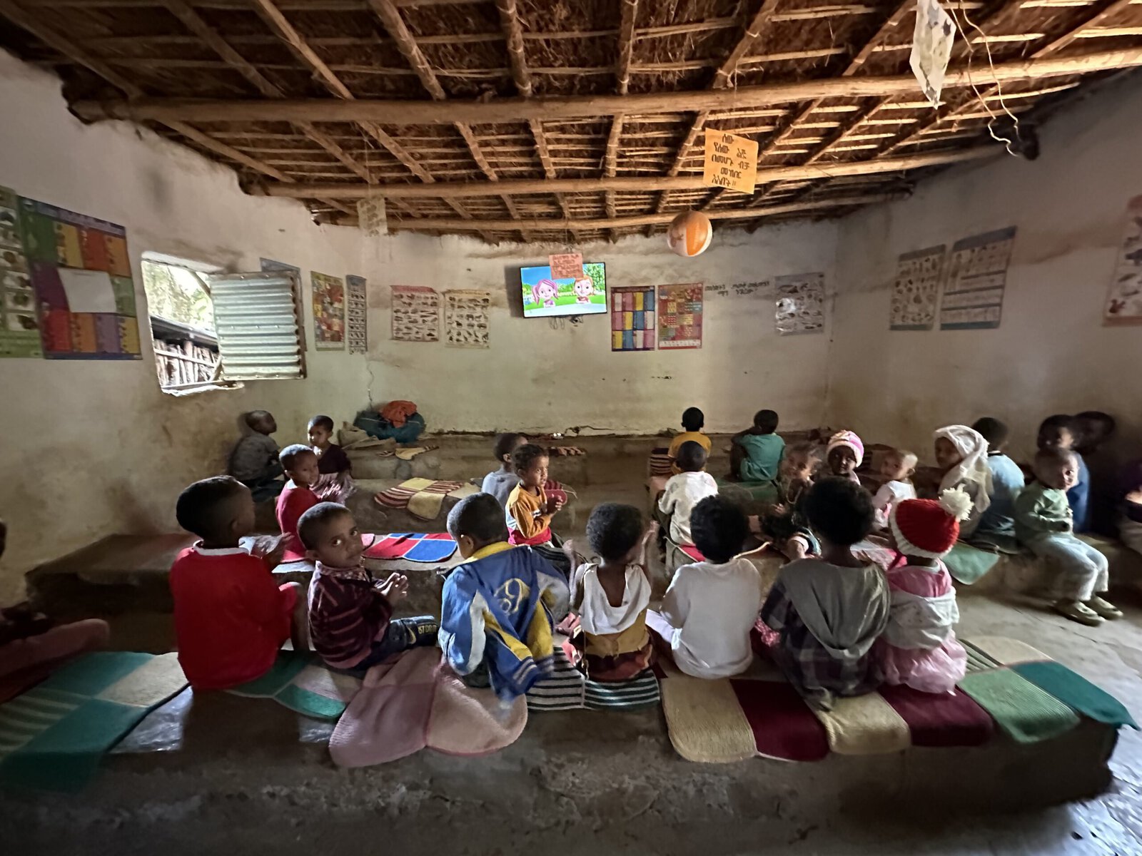 Students in Awra Amba sit in a classroom watching a TV.