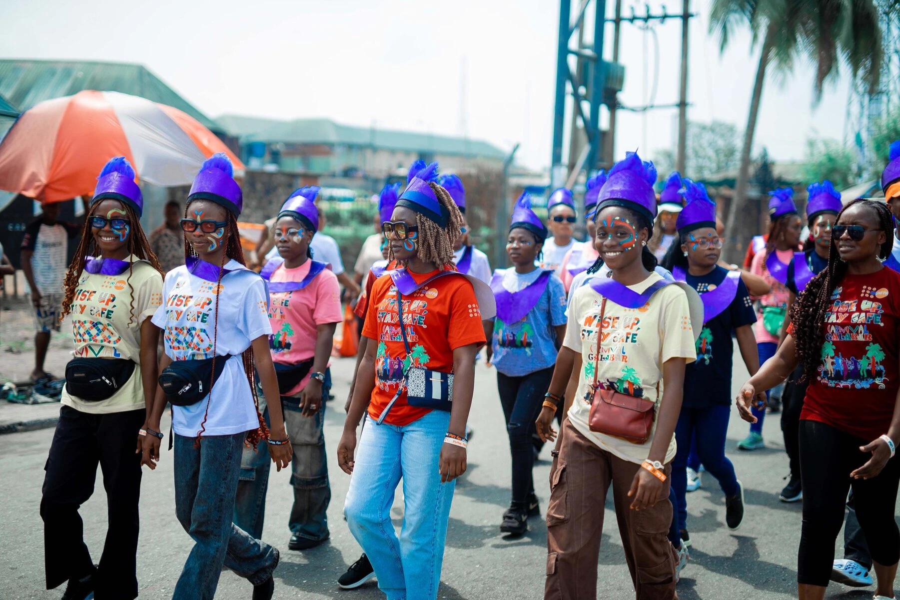 Volunteers and members of the Wise Up Band during the Carnival. They wear Wise Up t-shirts and purple hats.