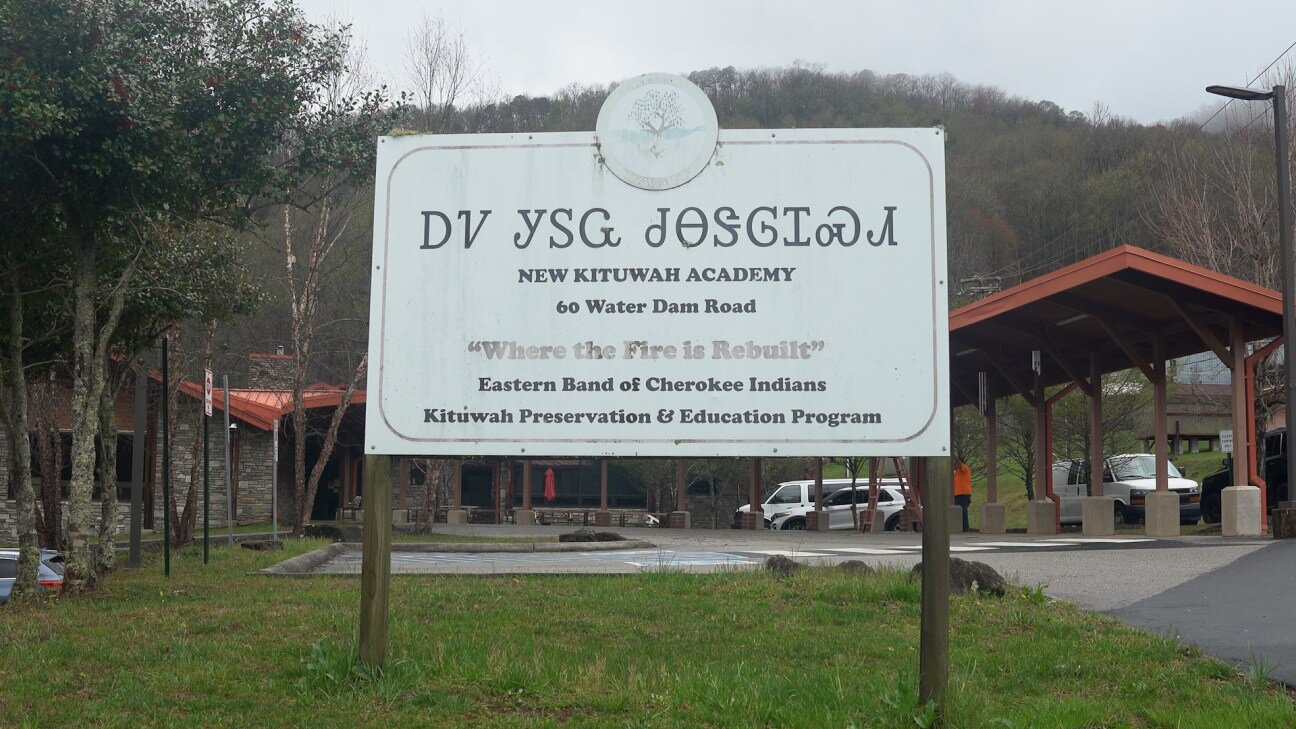 A sign outside the New Kituwah Academy, reading "Where the Fire is Rebuilt, Eastern Band of Cherokee Indians, Kituwah Preservation & Education Program"