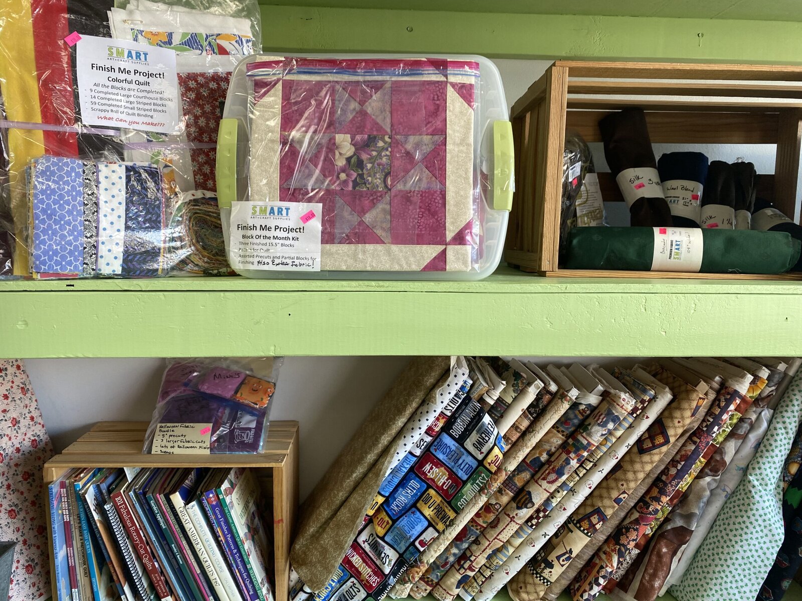 Leftover crafting supplies including other people's unfinished projects on shelves at a creative reuse store.