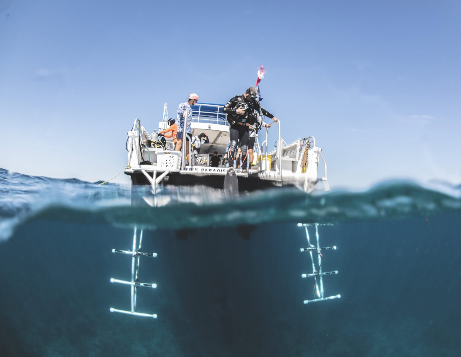 A half-underwater view shows a boat with divers standing on it.