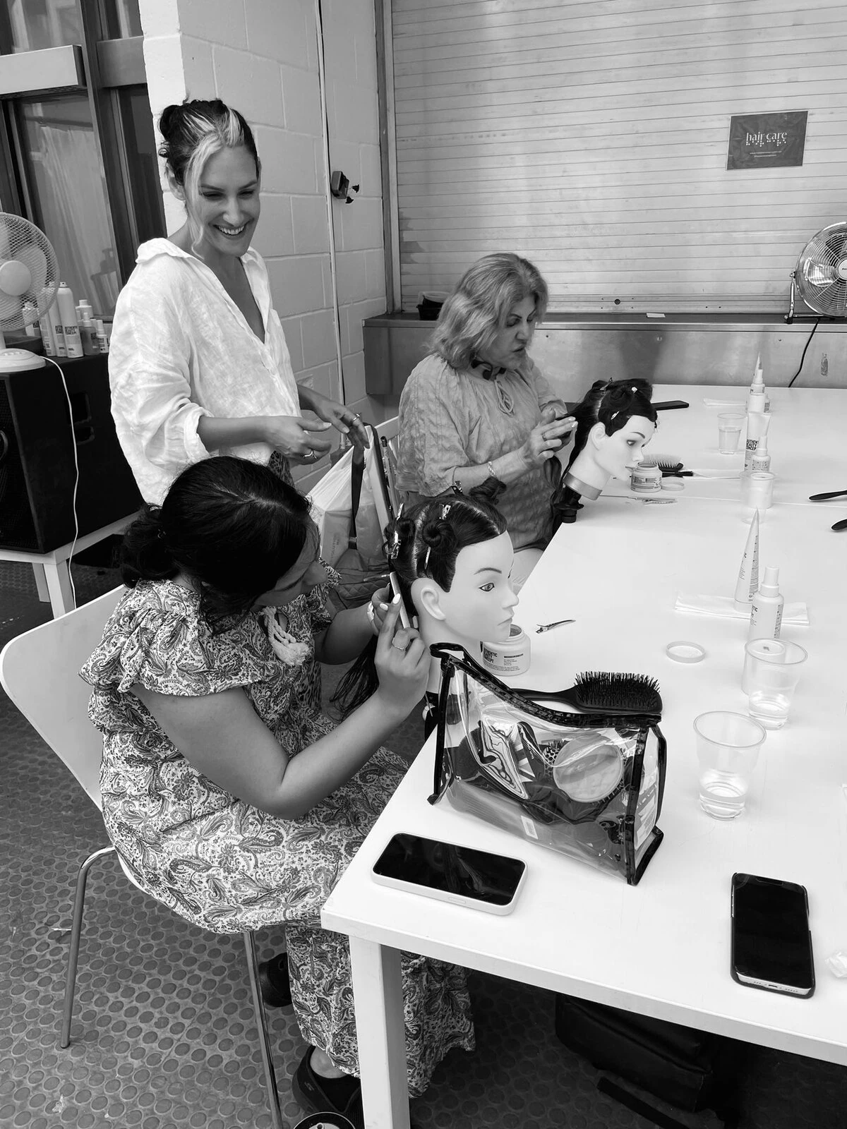 Attendees practice on mannequins at a Hair & Care workshop as Anna Cofone looks on. 