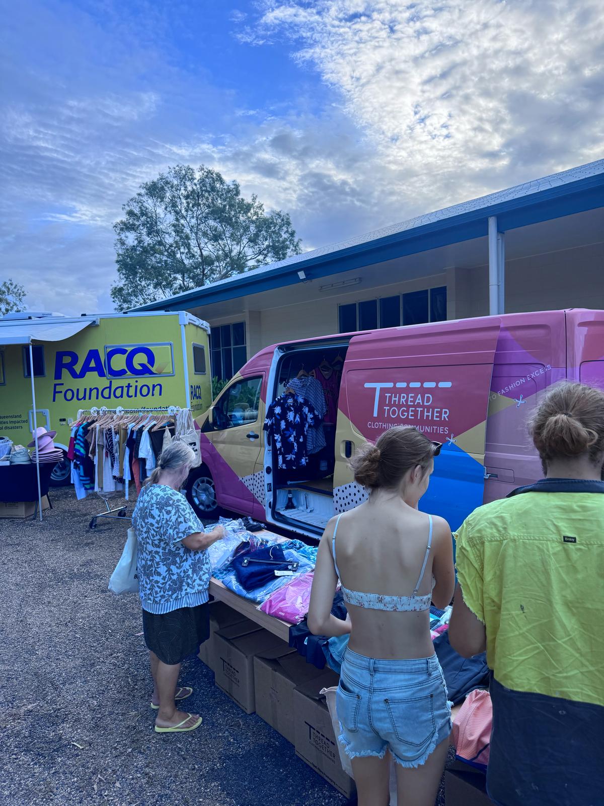 People browse clothes in front of a Thread Together van.