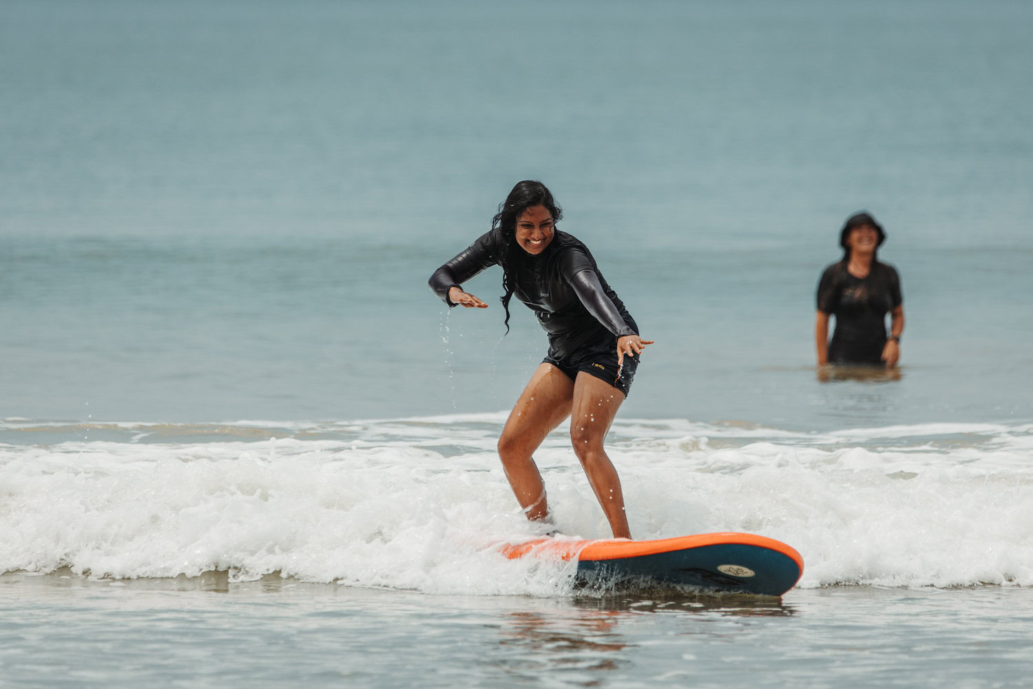 A woman surfs onto the beach.
