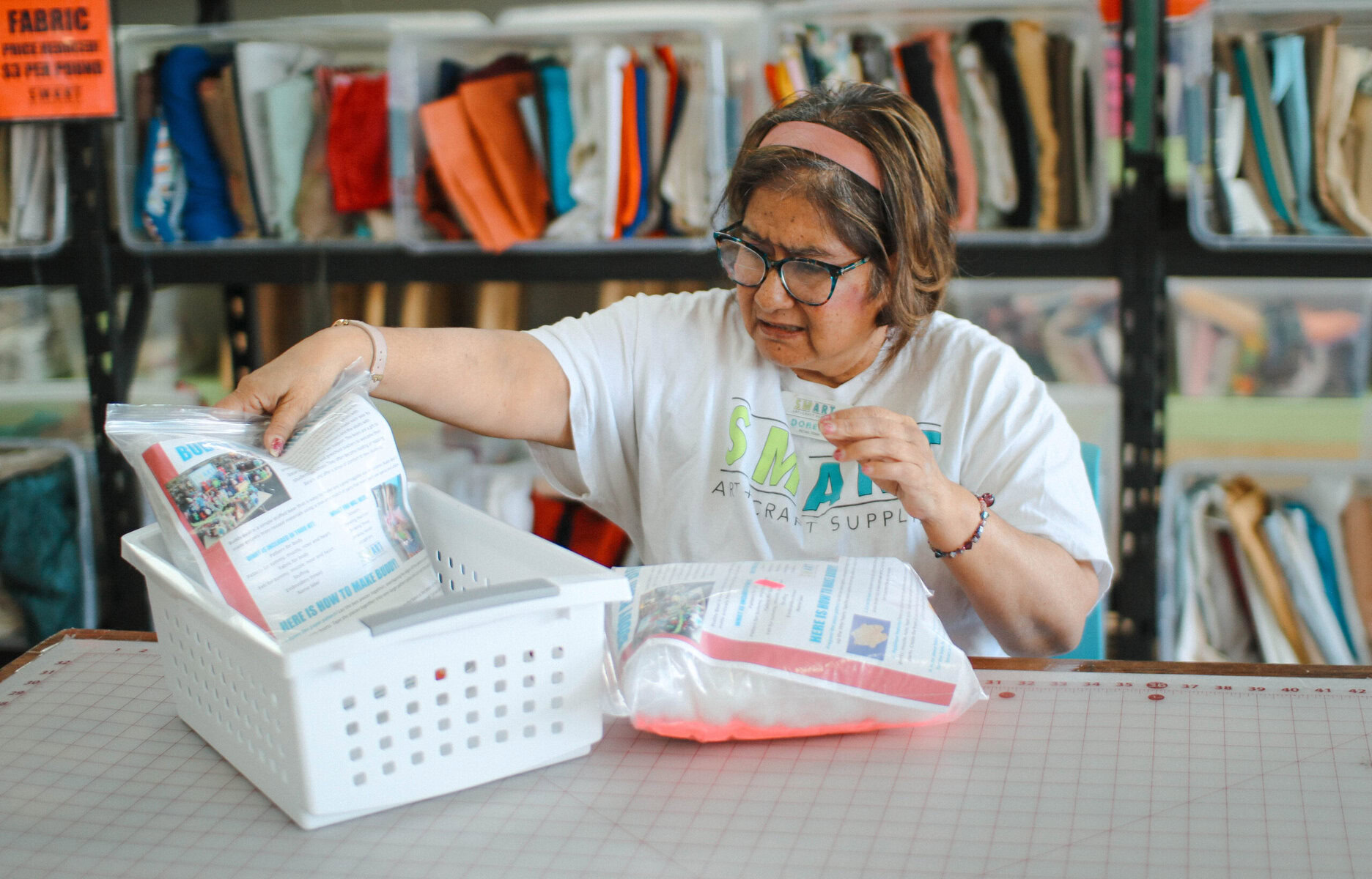 A woman working at a creative reuse center organizing materials at a table.