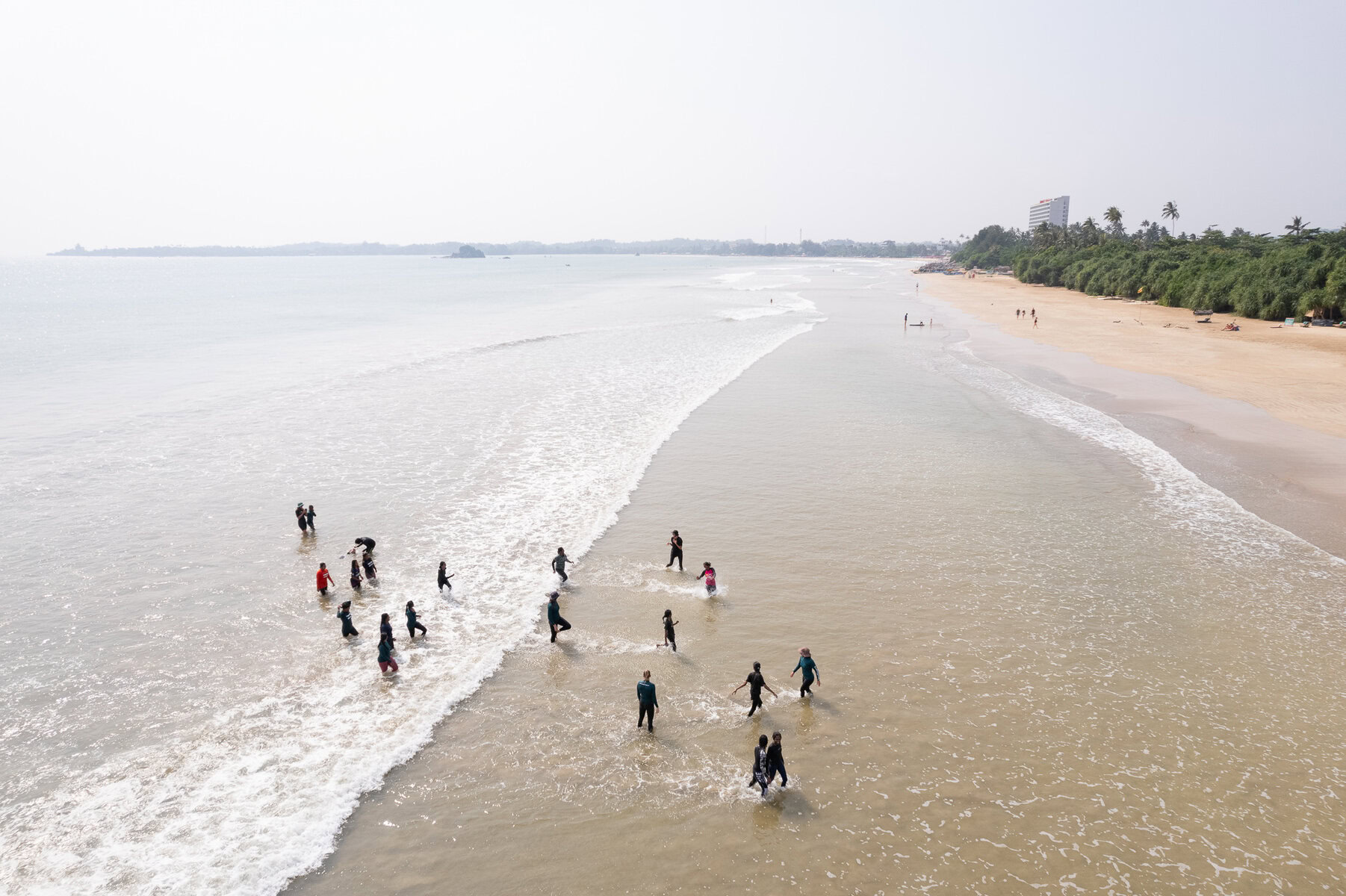 A drone view of a group of women gathered on a beach.