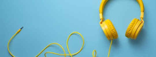 A pair of yellow headphones on a blue background.