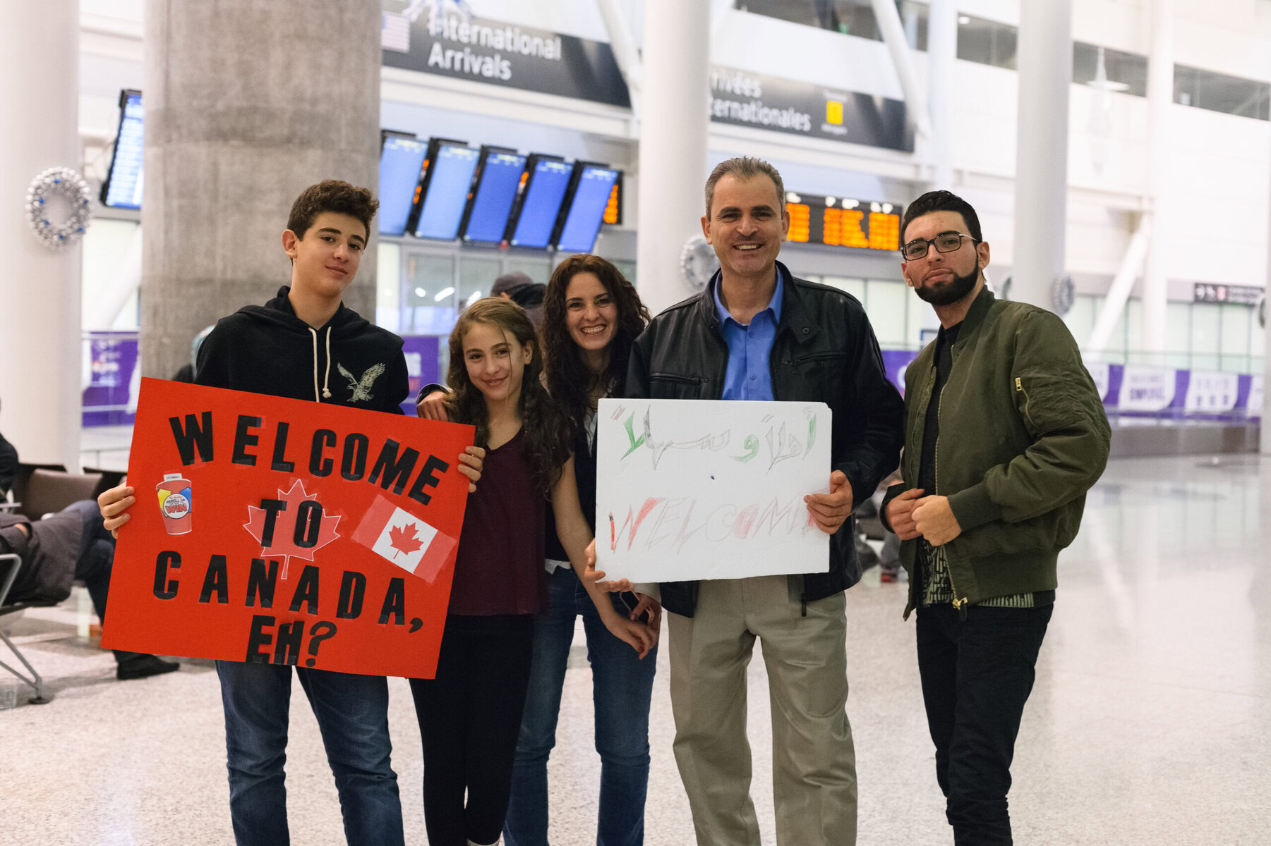 A family poses with signs to welcome immigrants.